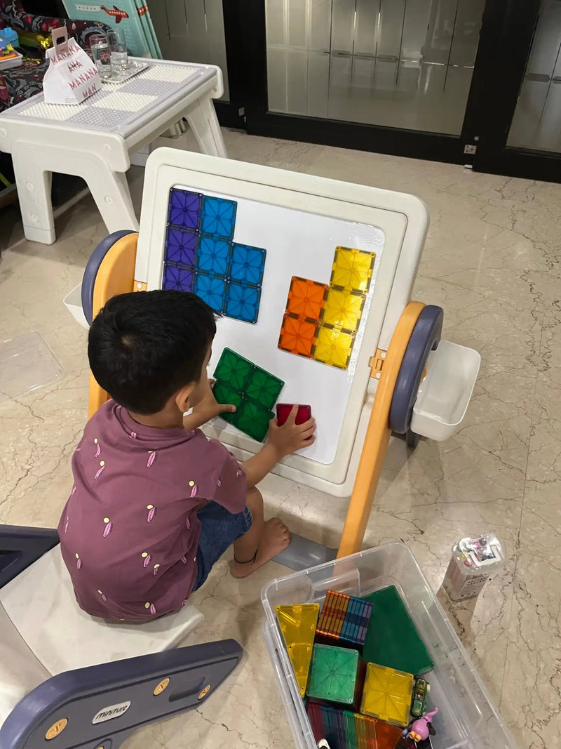A child constructing shapes on a magnetic drawing board.