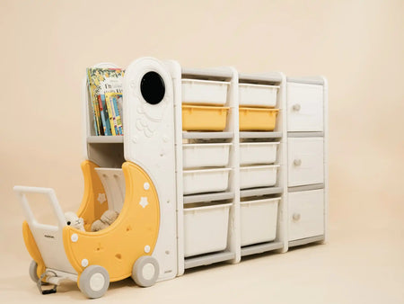 A modular children’s storage unit with shelves, bins, and a pull-out moon-shaped cart.